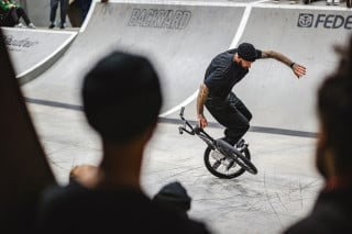 A BMX freestyle flatland rider competing at an indoor venue in the UK.